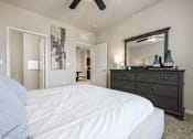 Thumbnail 11 of 40 - A bedroom with a large bed, a dresser, and a mirror.