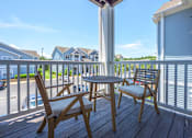 Thumbnail 13 of 40 - A wooden table and two chairs are on a deck with a view of a street and houses.