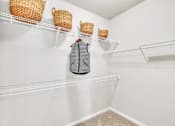 Thumbnail 22 of 39 - A grey vest hanging on a white shelf with two wicker baskets above it.