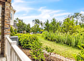 Thumbnail 23 of 39 - A house with a balcony overlooks a lush green yard.