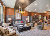 Thumbnail 26 of 48 - A living room with a grey couch and a brown chair.
