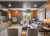 Thumbnail 39 of 48 - A modern living room with a grey sofa, a wooden coffee table, and a large chandelier.