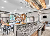 Thumbnail 30 of 39 - A modern kitchen with a granite countertop and a dining table with chairs.