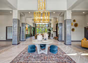 Thumbnail 40 of 48 - A large white table with blue chairs and a chandelier hangs in a spacious lobby.