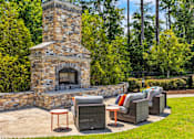 Thumbnail 36 of 39 - A stone fireplace is surrounded by outdoor furniture.