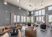 Thumbnail 30 of 38 - A spacious living room with brown leather furniture and large windows at Prosper Madison Oaks, Madison, AL