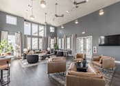 Thumbnail 32 of 38 - A modern living room with brown leather furniture and a flat screen TV mounted on the wall at Prosper Madison Oaks, Madison, AL