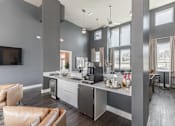 Thumbnail 35 of 38 - A modern kitchen with a large island and a flat-screen TV mounted on the wall at Prosper Madison Oaks, Madison, AL