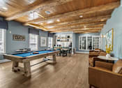 Thumbnail 24 of 41 - A pool table is surrounded by leather chairs in a room with wooden floors and ceiling.