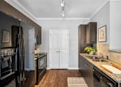 Thumbnail 6 of 41 - A kitchen with a black fridge and wooden floors.
