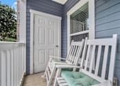 Thumbnail 18 of 41 - A white chair is placed on a green cushion on a porch.