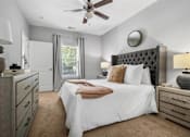Thumbnail 12 of 41 - A bedroom with a large bed, a ceiling fan, and a dresser with a lamp on top.