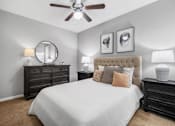 Thumbnail 14 of 41 - A bedroom with a large bed, a dresser, and a ceiling fan.
