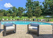 Thumbnail 32 of 40 - Two chairs are placed on a patio by a pool.
