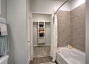 Thumbnail 7 of 30 - A bathroom with a white tub and a white shower curtain.
