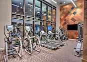 Thumbnail 23 of 30 - A gym with treadmills, exercise bikes, and elliptical machines.