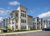Thumbnail 24 of 30 - A row of modern apartment buildings with a blue car parked in front.