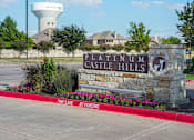 Thumbnail 2 of 30 - a stone sign with a water tower behind it in front of a parking lot