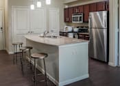 Thumbnail 21 of 30 - a kitchen with an island with stools and a stainless steel refrigerator