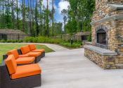 Thumbnail 4 of 14 - a concrete patio with orange couches and a stone fireplace at Sterling Creek, Richmond Hill