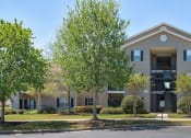 Thumbnail 1 of 10 - a large apartment building with trees in front of it at Mill Creek Run, Macon