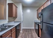 Thumbnail 7 of 10 - a kitchen with wood flooring and black appliances at Mill Creek Run, Georgia, 31216