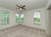 Thumbnail 17 of 50 - an empty living room with a ceiling fan and three windows at Legacy at Cibolo, Boerne, TX