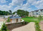 Thumbnail 8 of 50 - an exterior view of an apartment building with a green lawn and a pathway at Legacy at Cibolo, Texas
