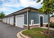 Thumbnail 44 of 74 - A row of garages with a tree in front of the first one at Waterleaf at Neely Ferry Apartments, South Carolina 29680