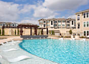 Thumbnail 16 of 30 - A large swimming pool in front of apartment buildings.