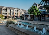 Thumbnail 5 of 30 - a fountain sits in front of a swimming pool with houses in the background