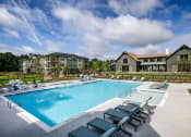 Thumbnail 20 of 32 - a swimming pool with chairs around it in front of a building at Bellary Flats Apartments, Summerville , 29486