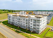 Thumbnail 18 of 20 - A large white apartment building with a green lawn in front.