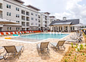 Thumbnail 17 of 20 - A pool surrounded by chairs and umbrellas in front of a building.