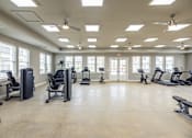 Thumbnail 14 of 20 - A spacious gym with various exercise equipment and a ceiling fan.