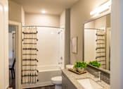 Thumbnail 6 of 20 - A bathroom with a white toilet, a sink, and a mirror.