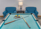 Thumbnail 21 of 35 - a game room with a pool table and two blue chairs