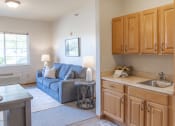 Thumbnail 6 of 35 - a living room with a couch and a kitchen with a sink