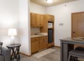 Thumbnail 16 of 35 - a small living room with a kitchen with a sink and a microwave