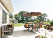 Thumbnail 30 of 35 - a backyard patio with a table and chairs and an umbrella