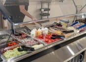 Thumbnail 31 of 35 - a buffet table with trays of food in a cafeteria