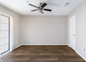 Thumbnail 15 of 28 - A room with a ceiling fan and wooden flooring.