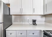 Thumbnail 11 of 28 - A kitchen with a refrigerator, a coffee maker, and a stove.