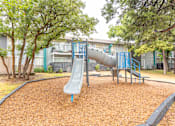 Thumbnail 5 of 19 - a playground with a slide and trees in front of a building