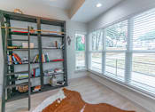 Thumbnail 9 of 19 - a living room with a large window and a book shelf