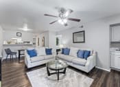 Thumbnail 10 of 17 - a living room with couches and a table and a ceiling fan
