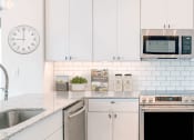 Thumbnail 1 of 23 - a kitchen with white cabinets and a sink and a refrigerator