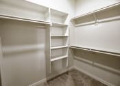 Thumbnail 10 of 21 - a walk in closet in a home with white walls and shelves