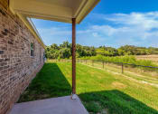 Thumbnail 20 of 21 - the back porch of a brick house with a yard and a fence