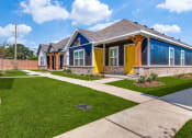Thumbnail 4 of 20 - a row of houses with blue and yellow doors and a sidewalk